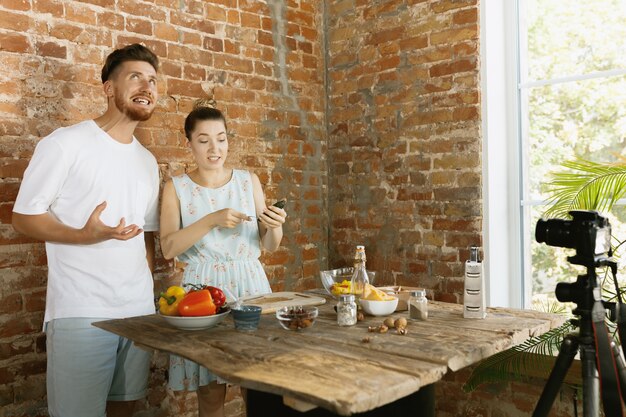 Casal jovem cozinhando e gravando vídeo ao vivo para vlog e redes sociais