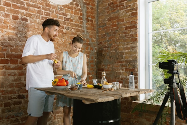 Casal jovem cozinhando e gravando vídeo ao vivo para vlog e redes sociais