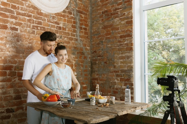 Casal jovem cozinhando e gravando vídeo ao vivo para vlog e redes sociais