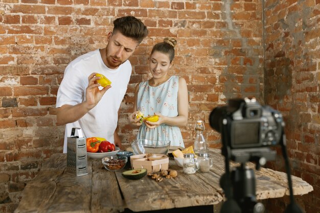 Casal jovem cozinhando e gravando vídeo ao vivo para vlog e redes sociais