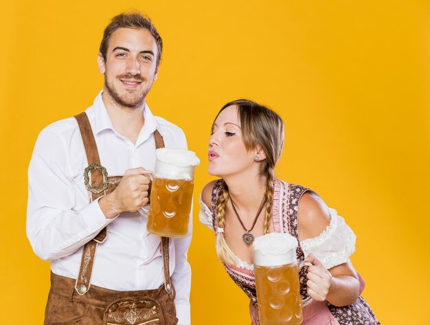 Casal jovem da Baviera com canecas de cerveja