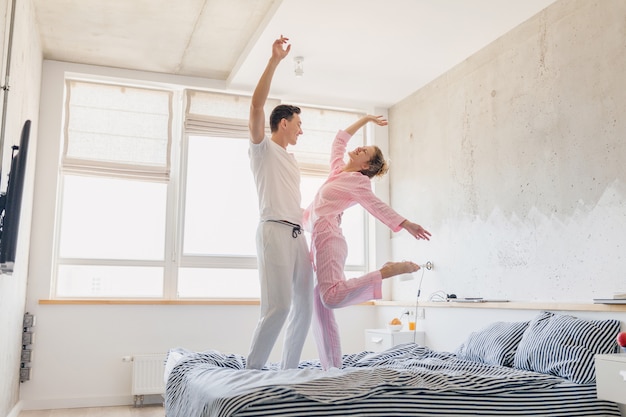 Casal jovem e bonito se divertindo na cama pela manhã fica junto em casa sozinho