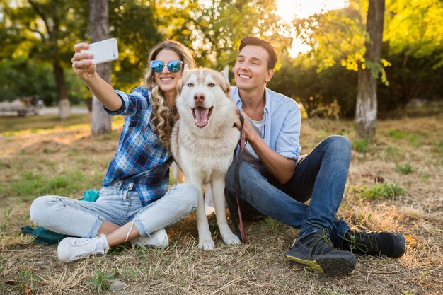 Casal jovem e elegante brincando com um cachorro no parque