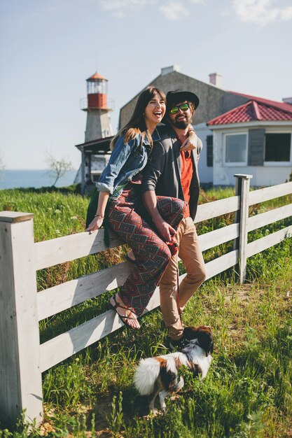 Casal jovem e elegante hippie apaixonado, caminhando com um cachorro no campo