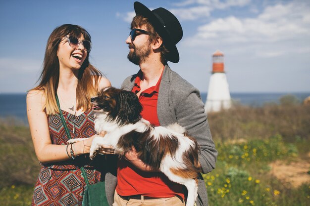 Casal jovem e elegante hippie apaixonado, caminhando com um cachorro no campo