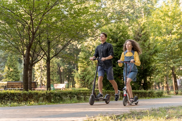 Foto grátis casal jovem e fofo andando de scooter ao ar livre