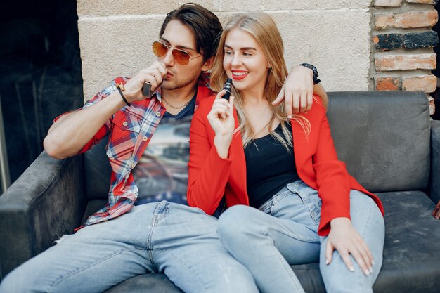 Casal jovem elegante com vape em um café