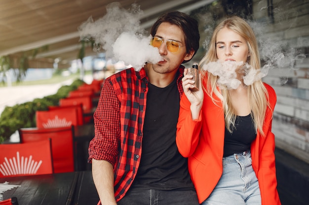 Casal jovem elegante com vape em uma cidade