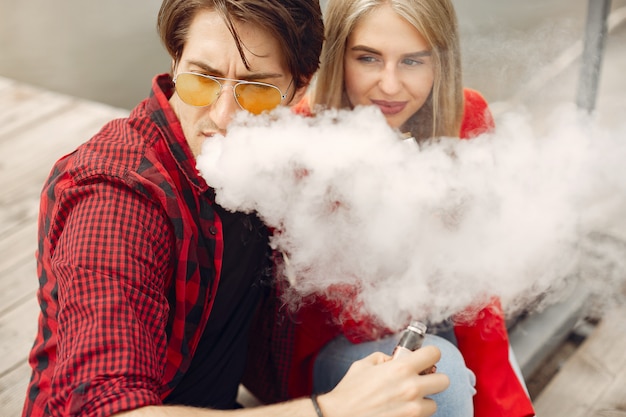 Casal jovem elegante com vape em uma cidade