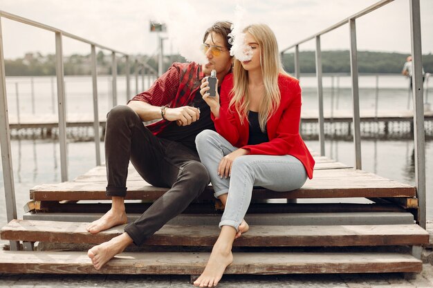 Casal jovem elegante com vape em uma cidade