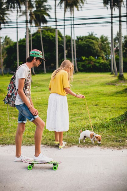 Casal jovem elegante hippie apaixonado de férias com cachorro e skate, se divertindo