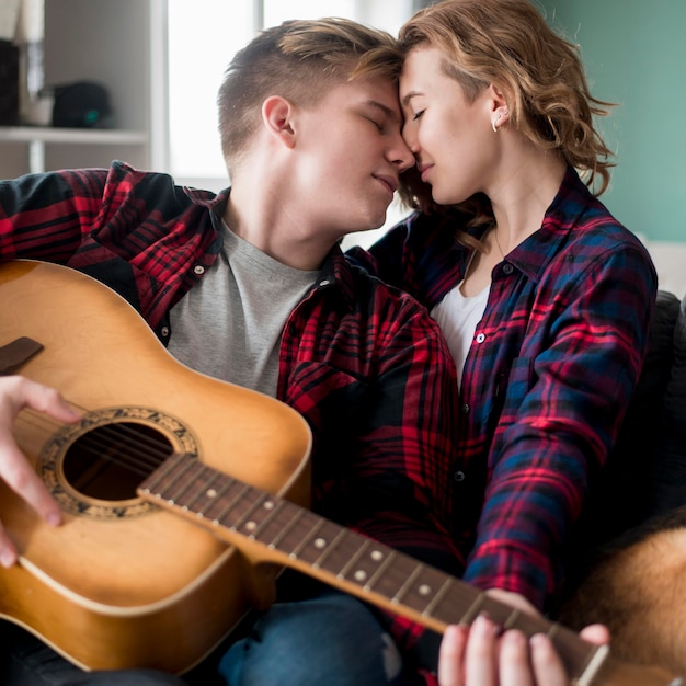 Foto grátis casal jovem em casa tocando violão