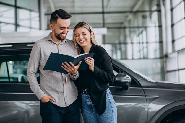 Casal jovem, escolhendo um carro em uma sala de show de carro