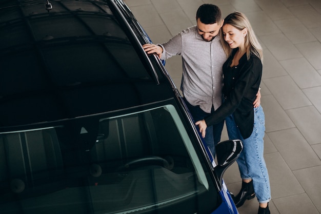 Casal jovem, escolhendo um carro em uma sala de show de carro