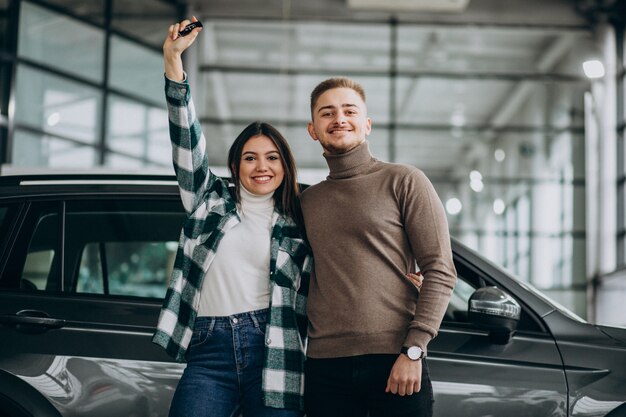 Casal jovem, escolhendo um carro em uma sala de show de carro