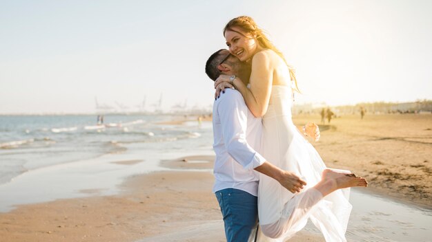 Casal jovem feliz adorável abraçando na praia