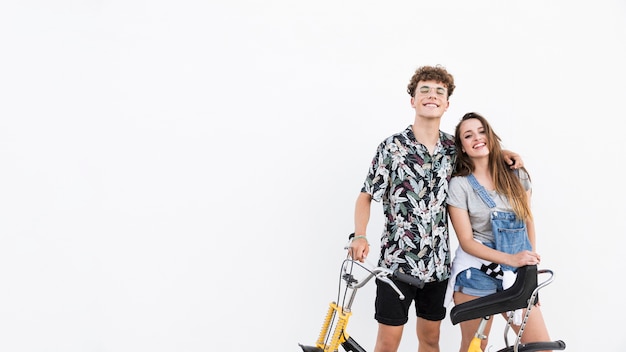 Casal jovem feliz com bicicleta em pano de fundo branco