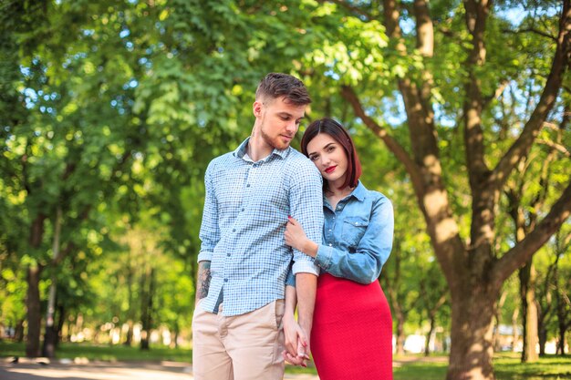 Casal jovem feliz no parque em pé e rindo no dia ensolarado