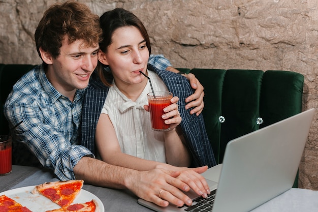 Casal jovem feliz no restaurante olhando para o laptop
