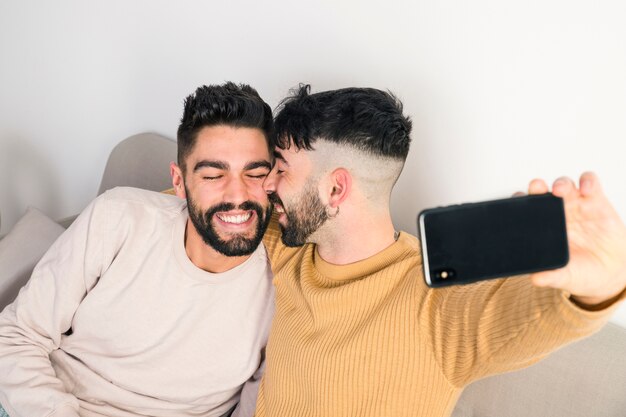 Casal jovem homossexual romântico tendo selfie no telemóvel