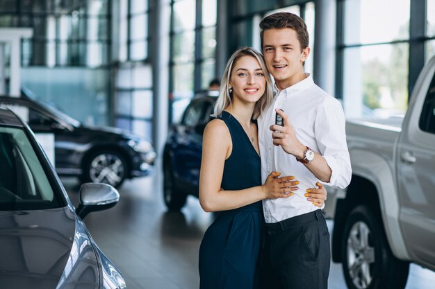 Casal jovem, revendo um carro em uma sala de exposições