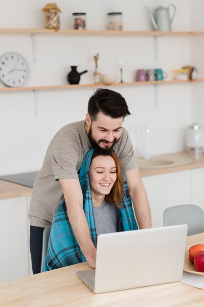 Casal jovem romântico abraçando e olhando para um laptop