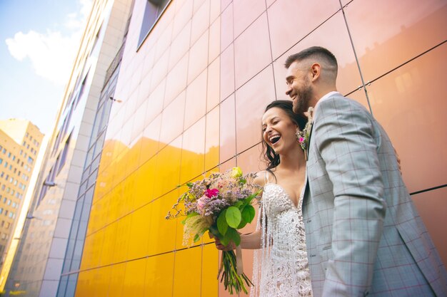 Casal jovem romântico caucasiano celebrando o casamento na cidade. Concurso noiva e noivo nas ruas da cidade moderna. Família, relação, conceito de amor