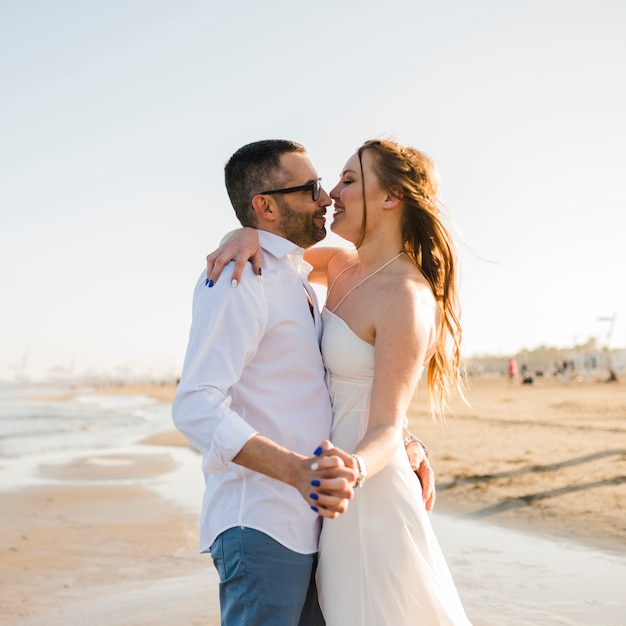 Casal jovem romântico, segurando a mão do outro, apreciando na praia