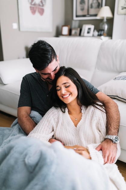 Casal jovem romântico sentado perto do sofá branco