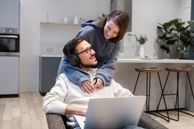 Casal juntos na cozinha trabalhando em um laptop