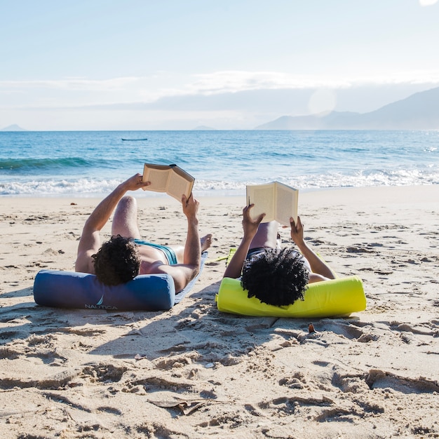 Foto grátis casal lendo na praia