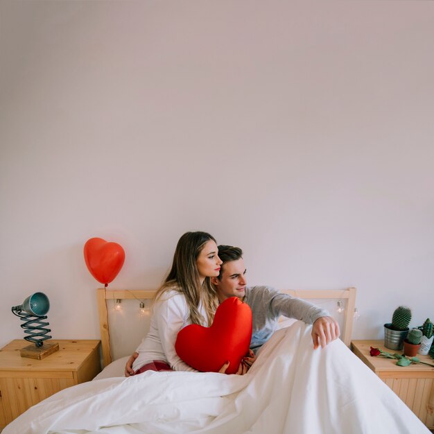 Casal lindo sentado na cama com o coração