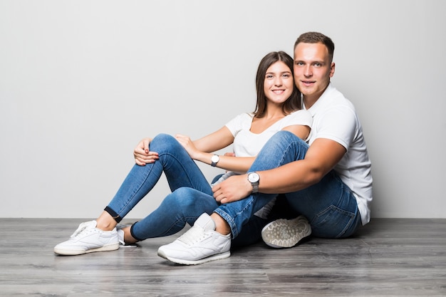 Foto grátis casal muito elegante se abraçando enquanto está sentado no chão, isolado no fundo branco