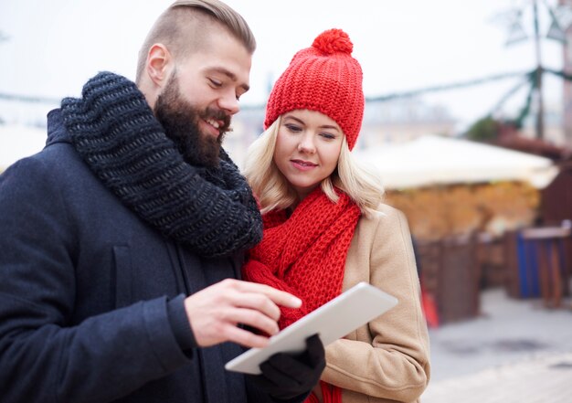 Casal navegando em tablet digital no inverno