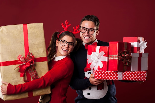 Casal nerd feliz segurando muitos presentes de natal