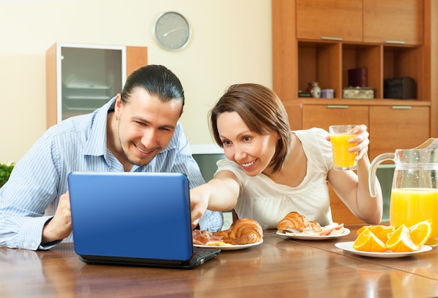 Casal olhando e-mai durante o café da manhã