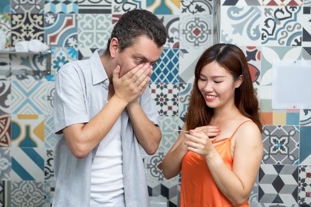 Casal olhando o teste de gravidez no banheiro