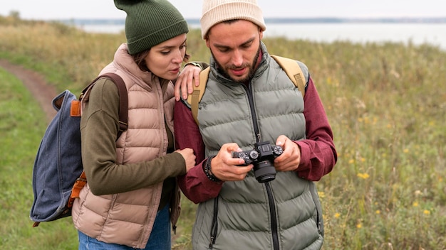 Casal olhando para uma câmera digital na natureza