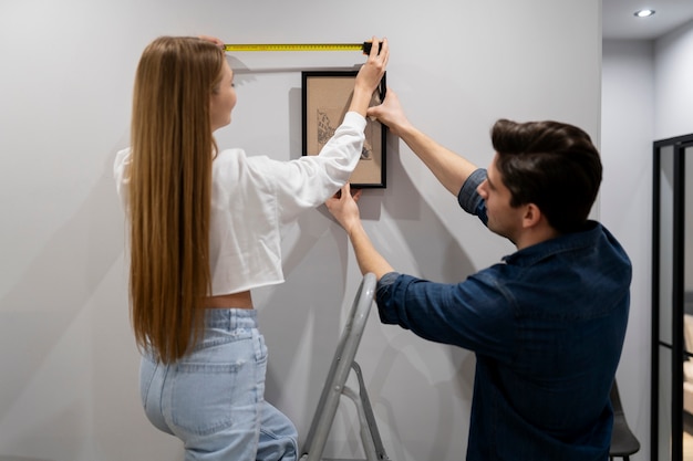 Foto grátis casal pendurado quadro na parede