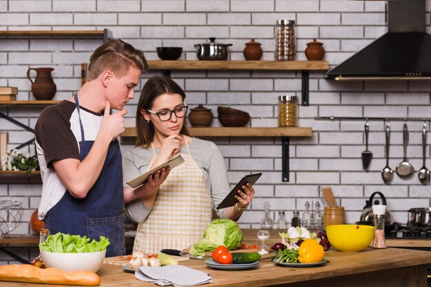 Casal pensativo com comprimidos na cozinha