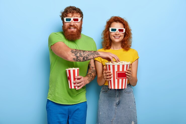 Foto grátis casal positivo vai ao cinema tarde da noite, come uma pipoca deliciosa