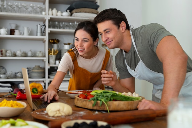 Foto grátis casal preparando e cozinhando pizza vegetariana na cozinha juntos