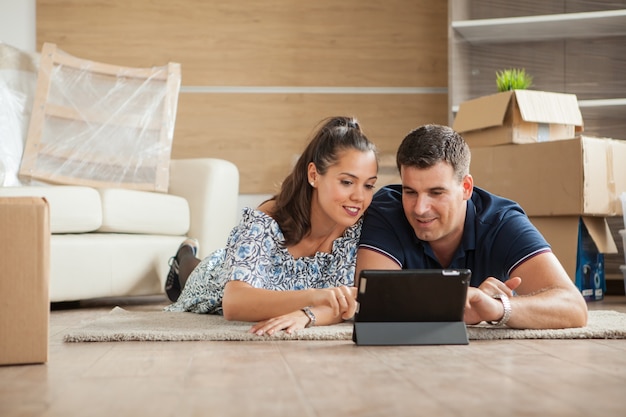Casal que acabou de se mudar para a nova casa está comprando móveis online em um tablet PC