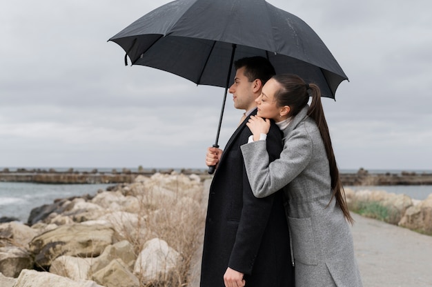 Casal romântico com tiro médio de guarda-chuva