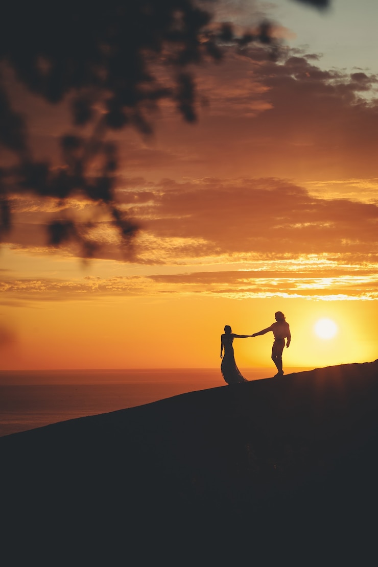 Foto grátis casal romântico de mãos dadas na costa do mar durante o pôr do sol