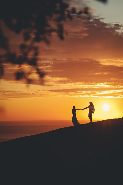 Casal romântico de mãos dadas na costa do mar durante o pôr do sol