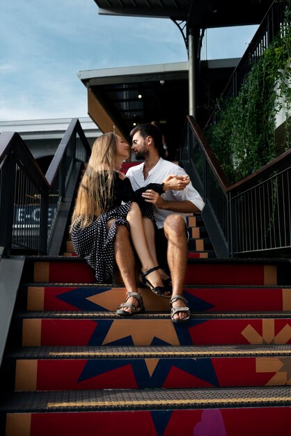 Casal romântico de tiro completo sentado na escada