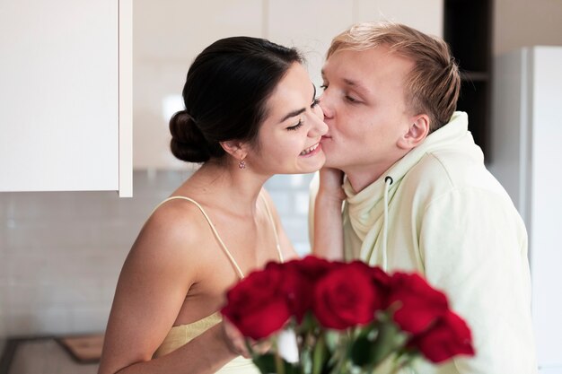 Casal romântico em casa comemorando o dia dos namorados com um buquê de lindas rosas vermelhas