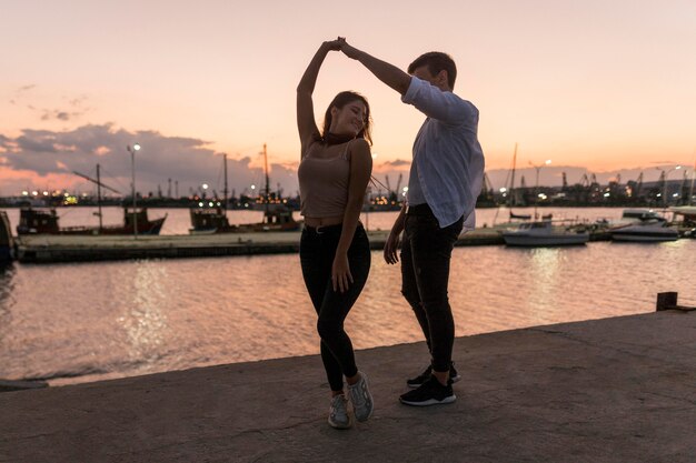 Casal romântico saindo ao pôr do sol no porto