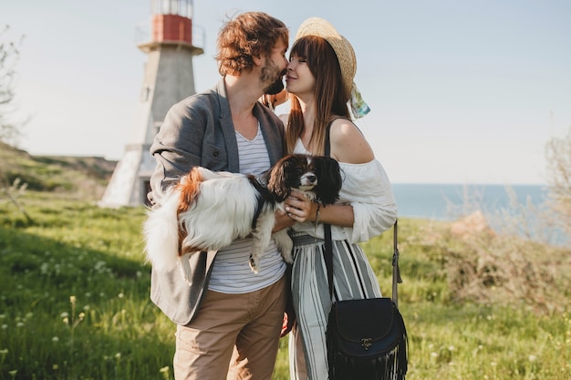 Casal se beijando, moderno e elegante, apaixonado, caminhando com o cachorro no campo